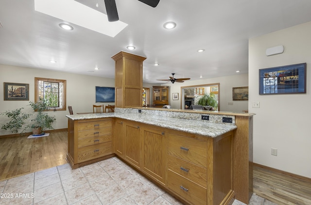 kitchen featuring light stone countertops, ceiling fan, brown cabinetry, and recessed lighting