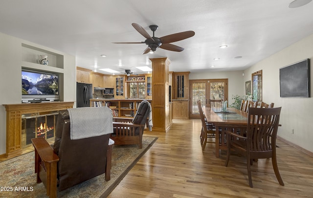 dining area featuring recessed lighting, a glass covered fireplace, ceiling fan, light wood-type flooring, and baseboards