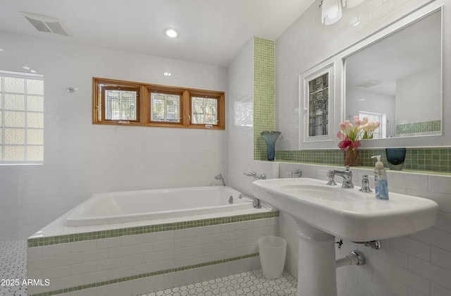 bathroom featuring a garden tub, visible vents, tile walls, and tile patterned floors