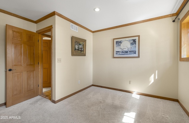 carpeted spare room with ornamental molding, visible vents, and baseboards