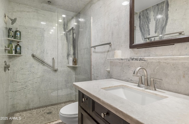 bathroom with a stall shower, tile walls, vanity, and toilet