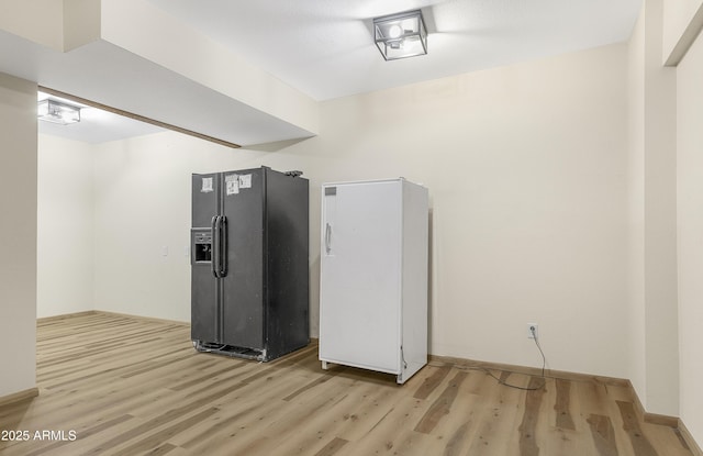 kitchen featuring light wood-style floors, black fridge with ice dispenser, and baseboards