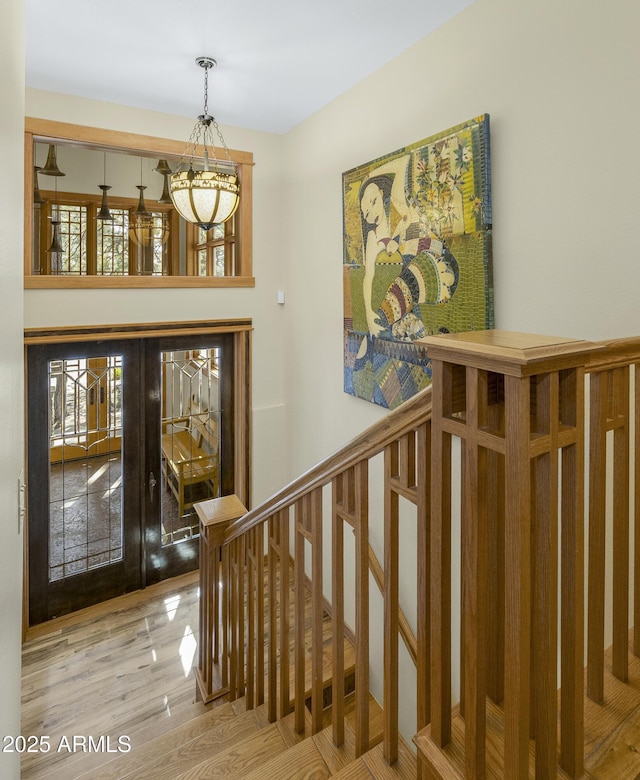 stairs with wood finished floors and french doors