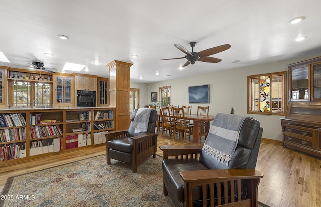 living area featuring recessed lighting, a skylight, wood finished floors, a ceiling fan, and baseboards