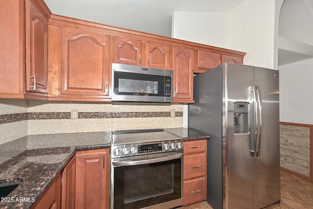 5226 W Pontiac Dr, Glendale, AZ 85308 - kitchen with dark stone countertops, light tile patterned floors, brown cabinetry, and appliances with stainless steel finishes