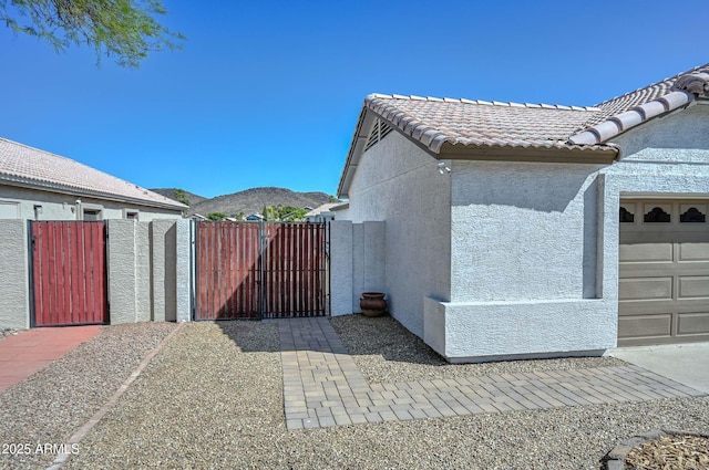 5226 W Pontiac Dr, Glendale, AZ 85308 - view of side of home with a tiled roof, a garage, stucco siding, a gate, and a mountain view