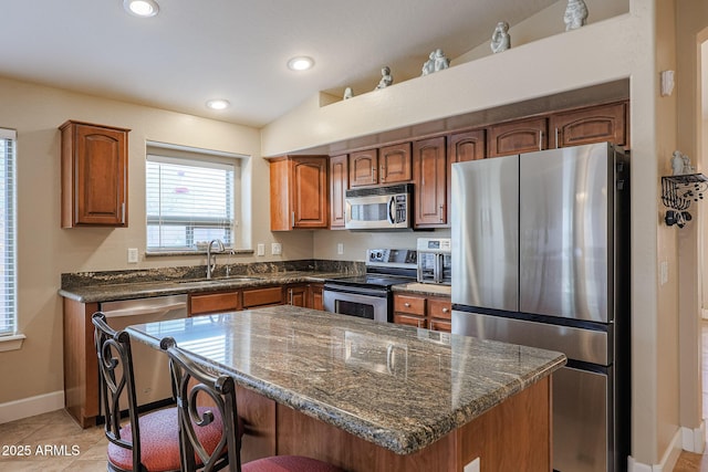 kitchen with sink, stainless steel appliances, a kitchen breakfast bar, lofted ceiling, and a kitchen island