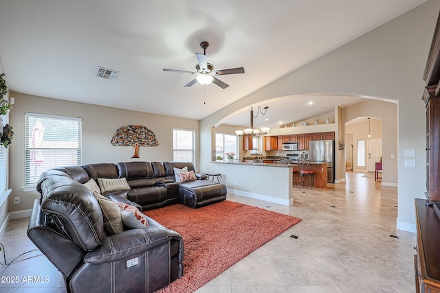 living room featuring lofted ceiling, light tile patterned flooring, and ceiling fan with notable chandelier