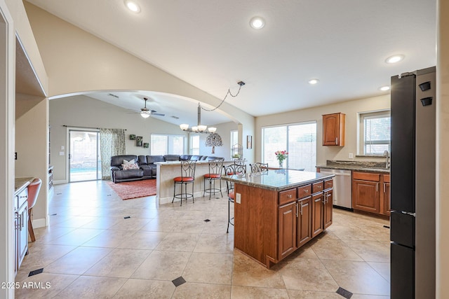 kitchen with appliances with stainless steel finishes, vaulted ceiling, decorative light fixtures, a kitchen island, and a breakfast bar area