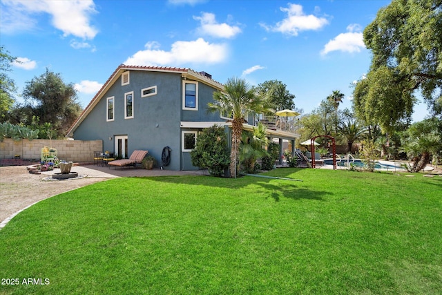 back of property featuring stucco siding, a lawn, fence, a fenced in pool, and a patio area