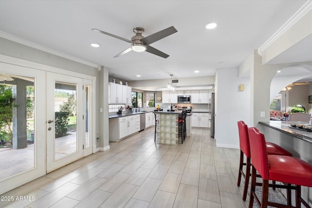 kitchen featuring stainless steel appliances, dark countertops, a breakfast bar area, and crown molding