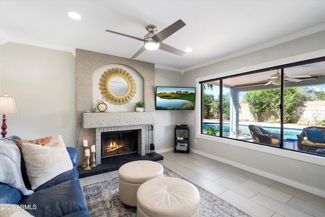 living room featuring a brick fireplace, baseboards, ornamental molding, recessed lighting, and a ceiling fan