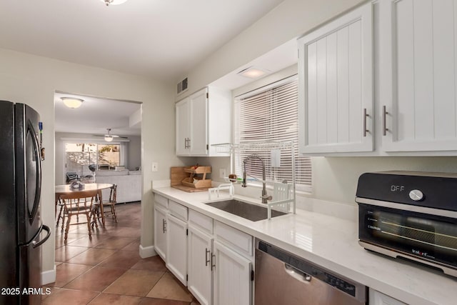 kitchen featuring sink, white cabinetry, tile patterned flooring, black fridge, and stainless steel dishwasher