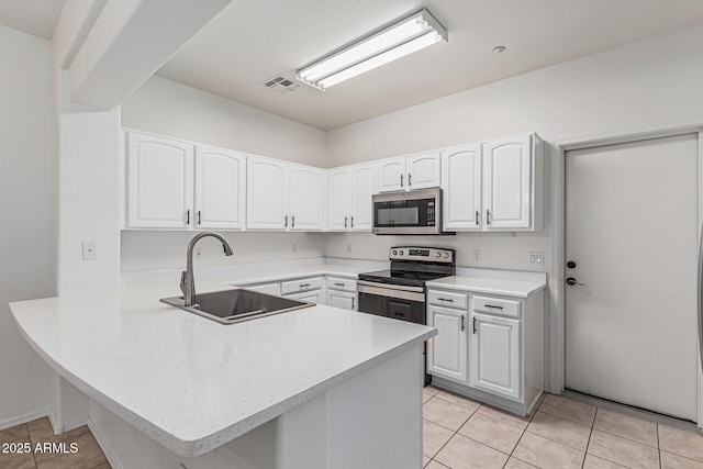 kitchen featuring a peninsula, light countertops, white cabinets, stainless steel appliances, and a sink