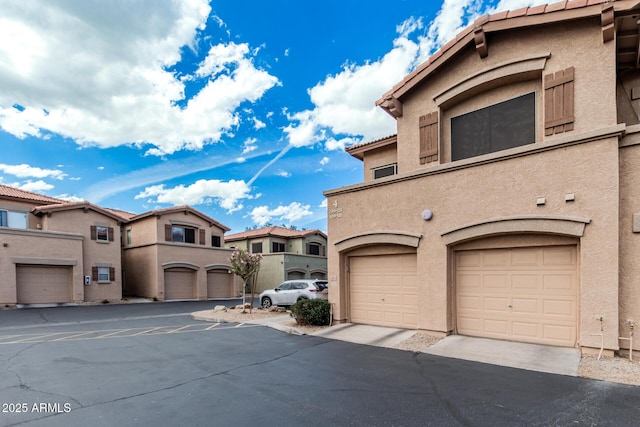 view of front of home featuring a tiled roof, a garage, stucco siding, and a residential view