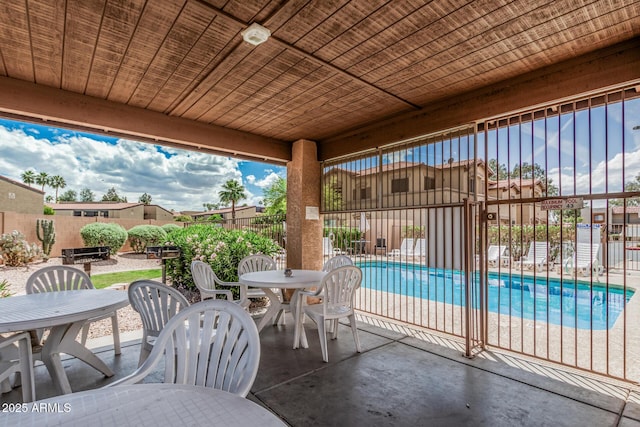 view of patio / terrace with a community pool, fence, and outdoor dining area