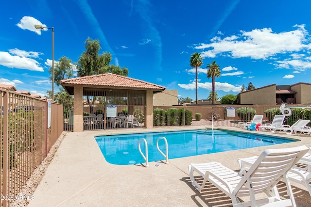 pool with a patio area and fence