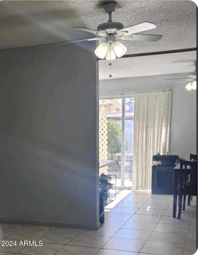 interior space featuring ceiling fan, tile patterned flooring, and a textured ceiling