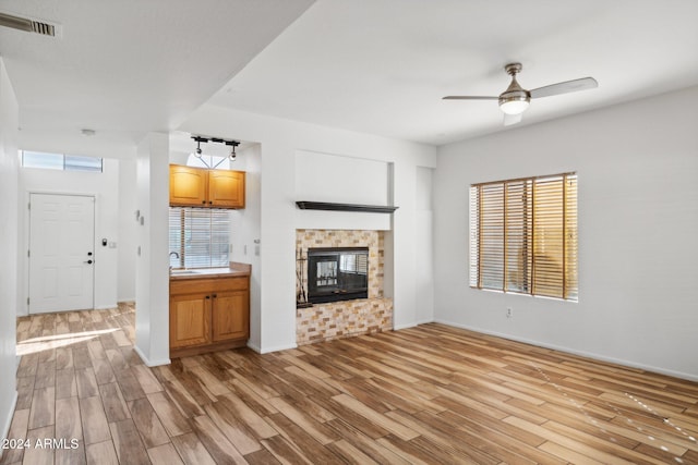 unfurnished living room with light hardwood / wood-style flooring, ceiling fan, and sink