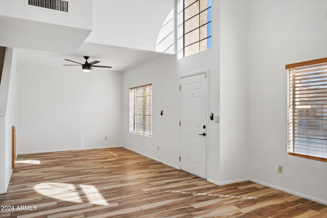 foyer entrance featuring plenty of natural light, ceiling fan, light wood-type flooring, and a high ceiling