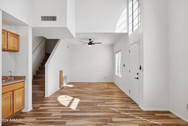 entrance foyer featuring ceiling fan, light hardwood / wood-style floors, sink, and a high ceiling