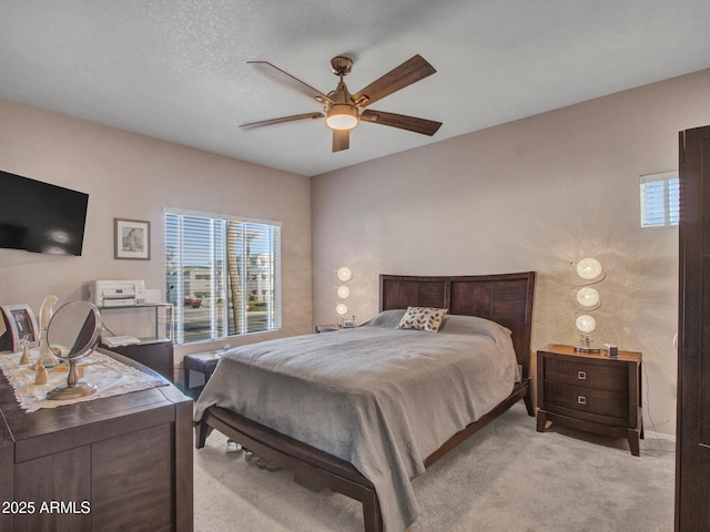 carpeted bedroom featuring ceiling fan and a textured ceiling