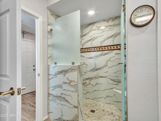 bathroom featuring wood-type flooring and tiled shower