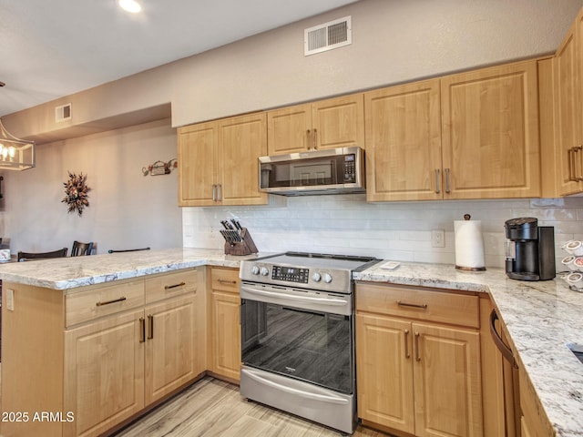 kitchen featuring kitchen peninsula, stainless steel appliances, tasteful backsplash, a notable chandelier, and light hardwood / wood-style flooring