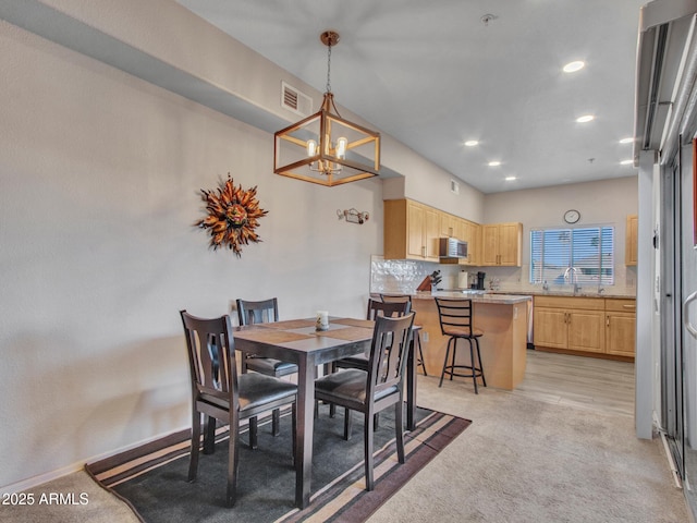 carpeted dining space featuring a notable chandelier and sink