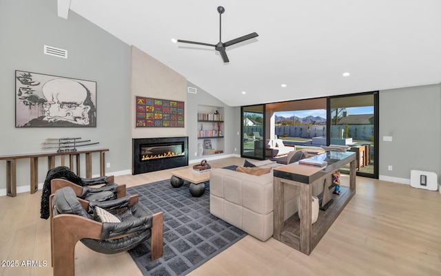 living room with ceiling fan, built in features, and light hardwood / wood-style flooring