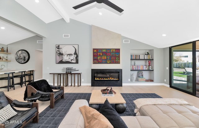 living room with ceiling fan, vaulted ceiling with beams, built in features, and hardwood / wood-style floors