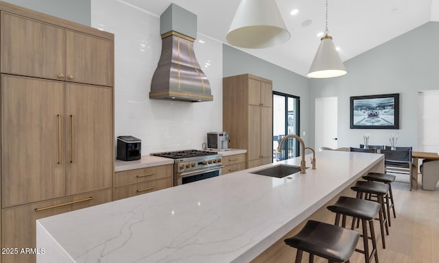 kitchen with a large island, island exhaust hood, decorative light fixtures, high end range, and sink