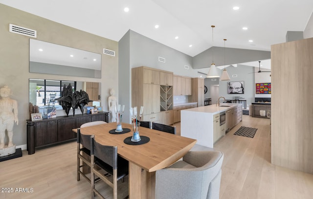 dining space with ceiling fan, lofted ceiling, light hardwood / wood-style floors, and sink