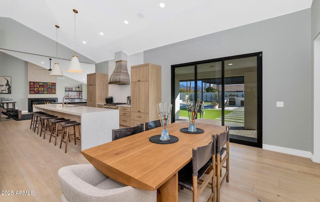 dining area with lofted ceiling, sink, and light hardwood / wood-style flooring