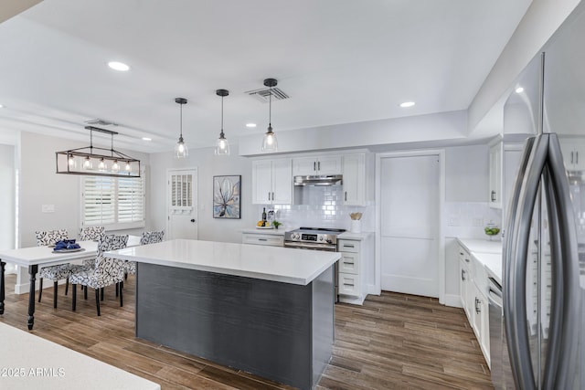 kitchen with visible vents, dark wood-style flooring, stainless steel appliances, light countertops, and under cabinet range hood