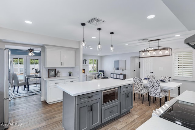 kitchen with visible vents, light countertops, gray cabinets, freestanding refrigerator, and built in microwave