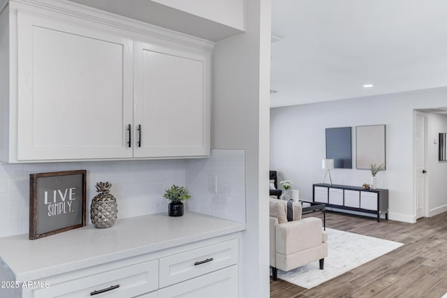 bar featuring baseboards, decorative backsplash, wood finished floors, and recessed lighting