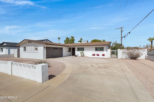 ranch-style house with concrete driveway, fence, an attached garage, and a gate