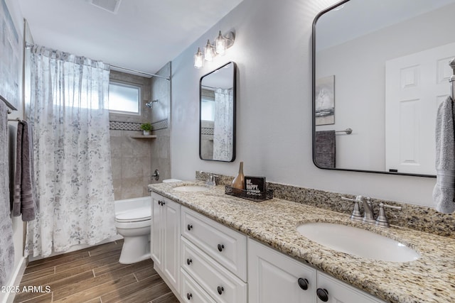 bathroom featuring wood tiled floor, a sink, shower / tub combo, and toilet