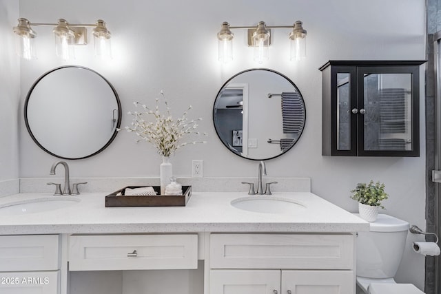 bathroom with double vanity, a sink, and toilet