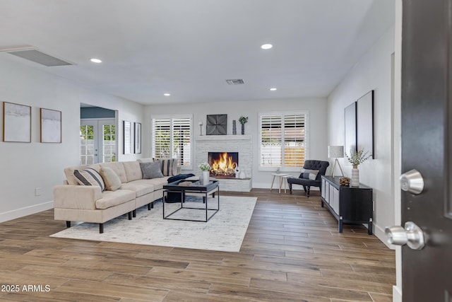 living room with a healthy amount of sunlight, a fireplace, visible vents, and wood finished floors