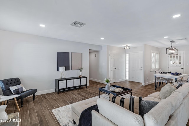 living room with baseboards, visible vents, a chandelier, and wood finished floors