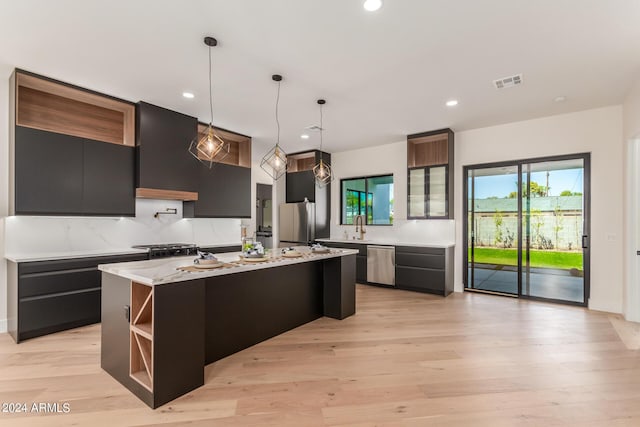 kitchen with a center island, decorative light fixtures, light hardwood / wood-style floors, dishwasher, and decorative backsplash