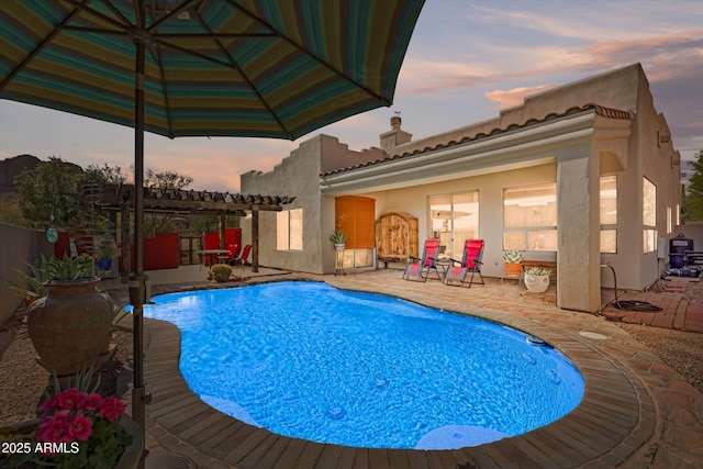 pool at dusk featuring a patio, a fenced in pool, and a pergola