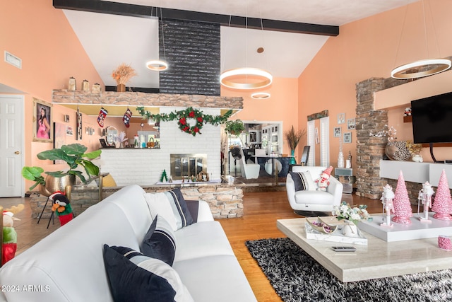 living room with hardwood / wood-style floors, beamed ceiling, high vaulted ceiling, and a brick fireplace