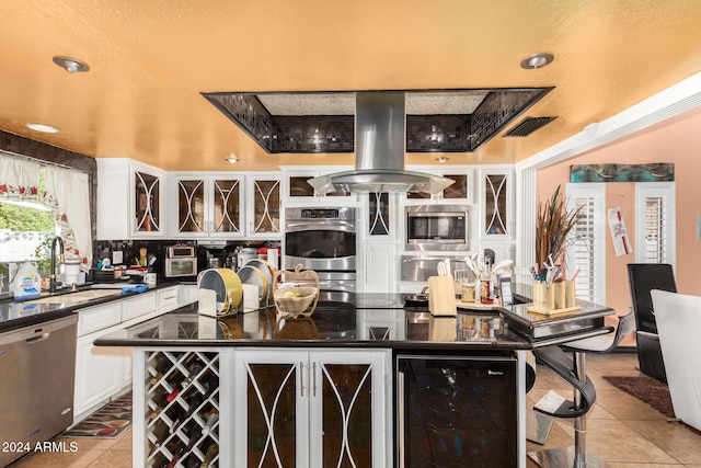 kitchen with island range hood, a center island, beverage cooler, and appliances with stainless steel finishes