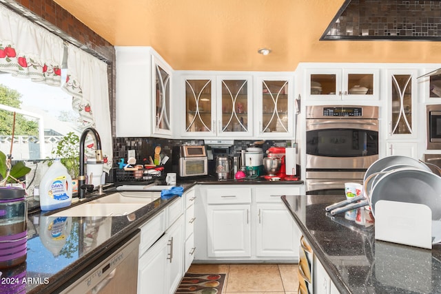 kitchen with white cabinets, stainless steel appliances, dark stone counters, and sink