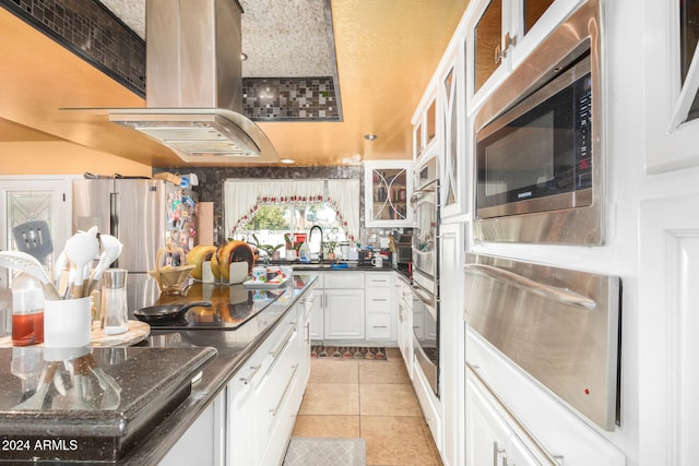 kitchen featuring light tile patterned floors, dark stone counters, extractor fan, white cabinets, and appliances with stainless steel finishes