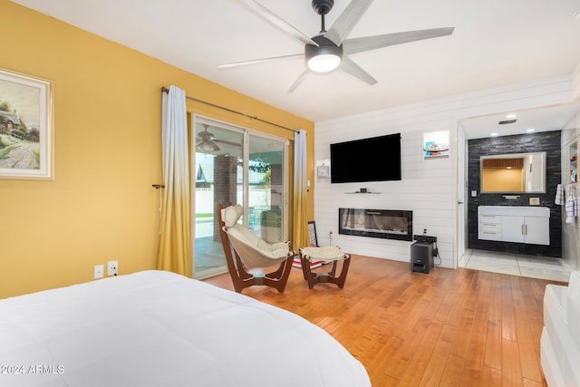 bedroom with ceiling fan, access to exterior, light wood-type flooring, and a fireplace