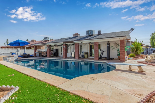 view of swimming pool with a patio area, ceiling fan, and a diving board